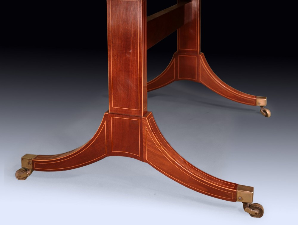 A George III mahogany sofa table featuring satinwood crossbanding, drop-leaf ends, two frieze drawers, and splayed legs on brass castors. View VII
