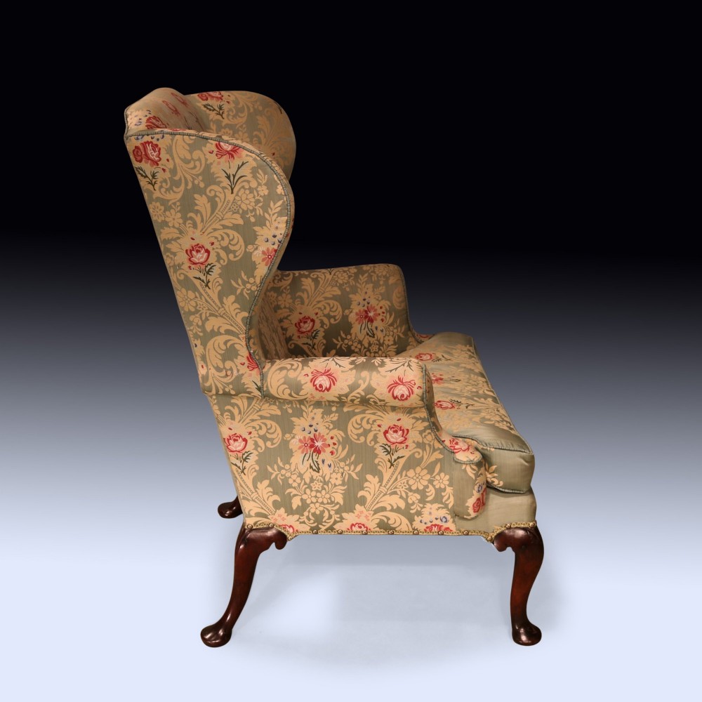 An early 18th-century wing armchair upholstered in patterned green and beige damask fabric with carved walnut cabriole legs. View III