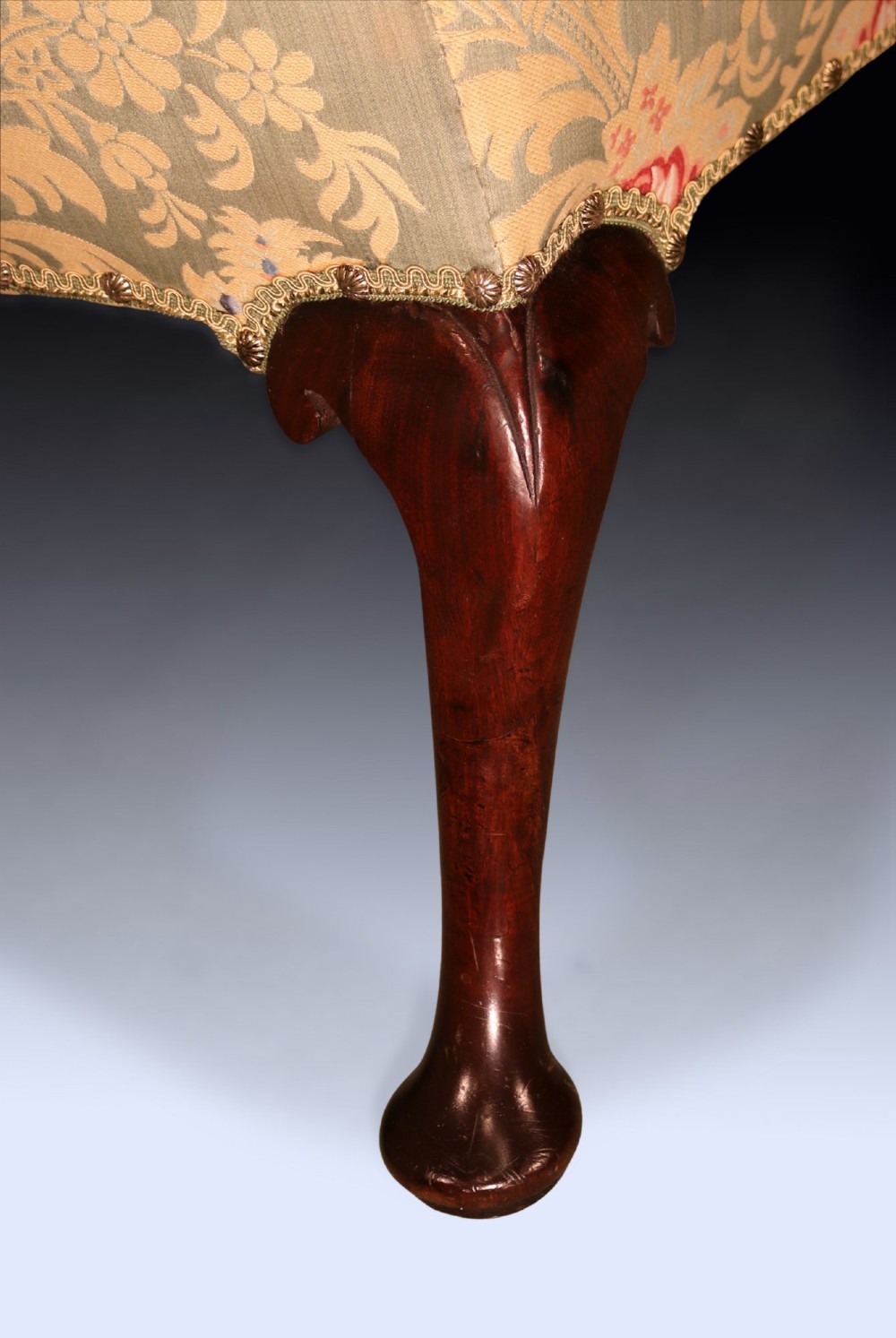 An early 18th-century wing armchair upholstered in patterned green and beige damask fabric with carved walnut cabriole legs. View V
