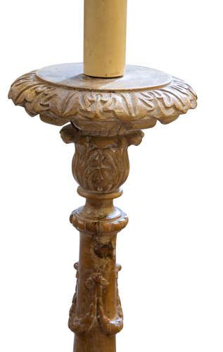 fig 2. A tall hand-carved pine torchere candlestick stand featuring a turned central column, carved leaf motifs, and a square pedestal base raised on sculpted feet.