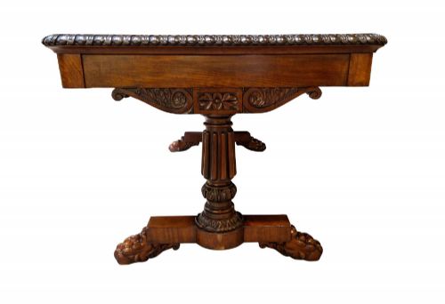 fig 2. A George IV mahogany partners writing table featuring a patterned top edge, three frieze drawers, carved pedestal supports, a turned stretcher, and claw feet.