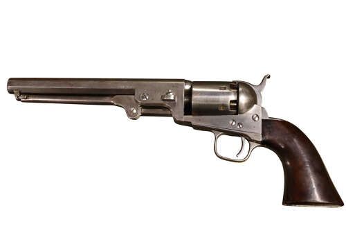 fig 1. An antique Colt Model 1851 Navy percussion revolver featuring a grey steel frame, an octagonal barrel, a six-shot cylinder, and a dark walnut grip.