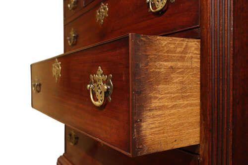 fig 2. A tall George III mahogany chest on chest featuring two stacked sections with graduated drawers, decorative pierced brass handles, and bracket feet.