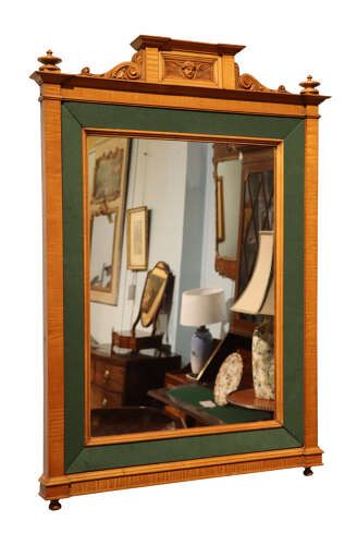 fig 1. An Edwardian satinwood rectangular wall mirror featuring an inner green fabric border, top pediment with a carved cherub crest, and turned corner finials.