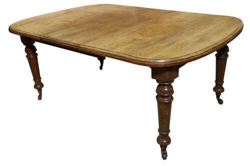 fig 1. A Victorian oak extending dining table featuring rounded D-ends, a removable centre leaf, and four turned legs on brass castors.
