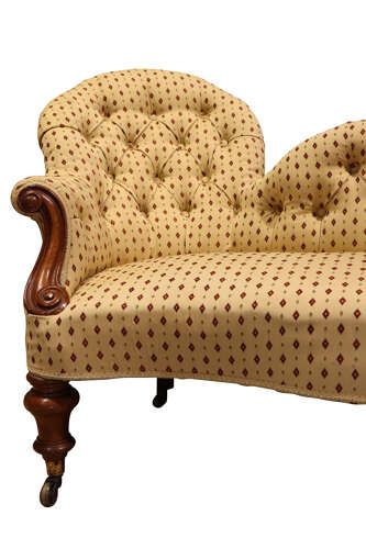 fig 1. A Victorian mahogany double-ended settee featuring deep-buttoned patterned yellow upholstery, carved scroll arms, and turned legs with brass castors.