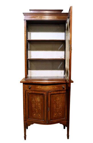 fig 1. An Edwardian inlaid mahogany display cabinet featuring a glazed top door with geometric tracery above a lower cupboard with floral marquetry.