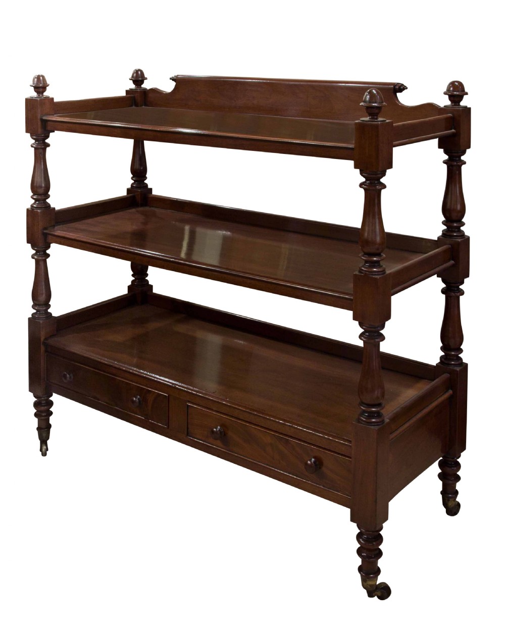 A nineteenth-century dark mahogany three-tier dumb waiter featuring turned support columns, two lower drawers, urn finials, and brass castors.