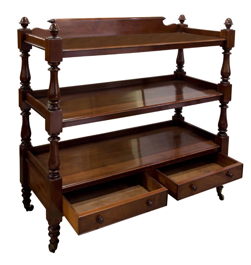 A nineteenth-century dark mahogany three-tier dumb waiter featuring turned support columns, two lower drawers, urn finials, and brass castors. View III