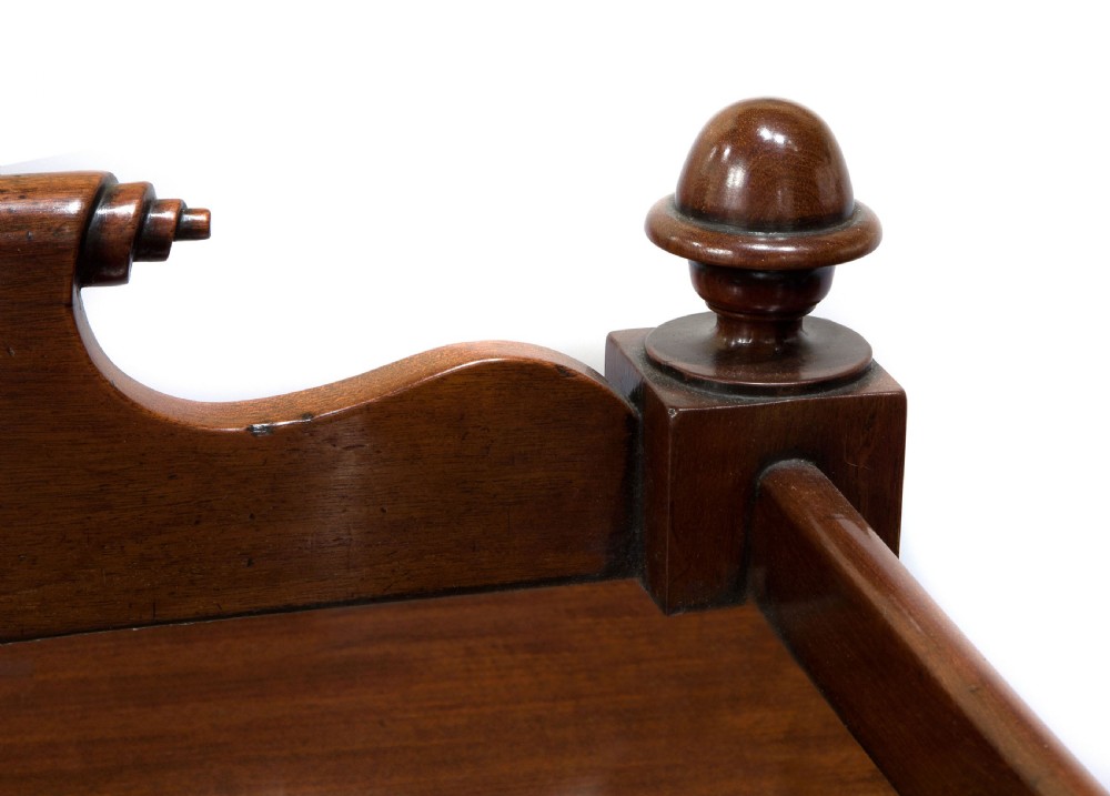 A nineteenth-century dark mahogany three-tier dumb waiter featuring turned support columns, two lower drawers, urn finials, and brass castors. View VI