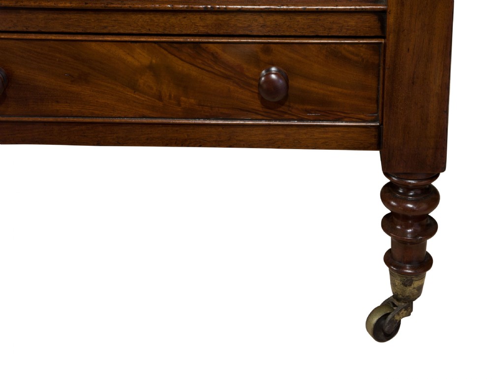 A nineteenth-century dark mahogany three-tier dumb waiter featuring turned support columns, two lower drawers, urn finials, and brass castors. View VII