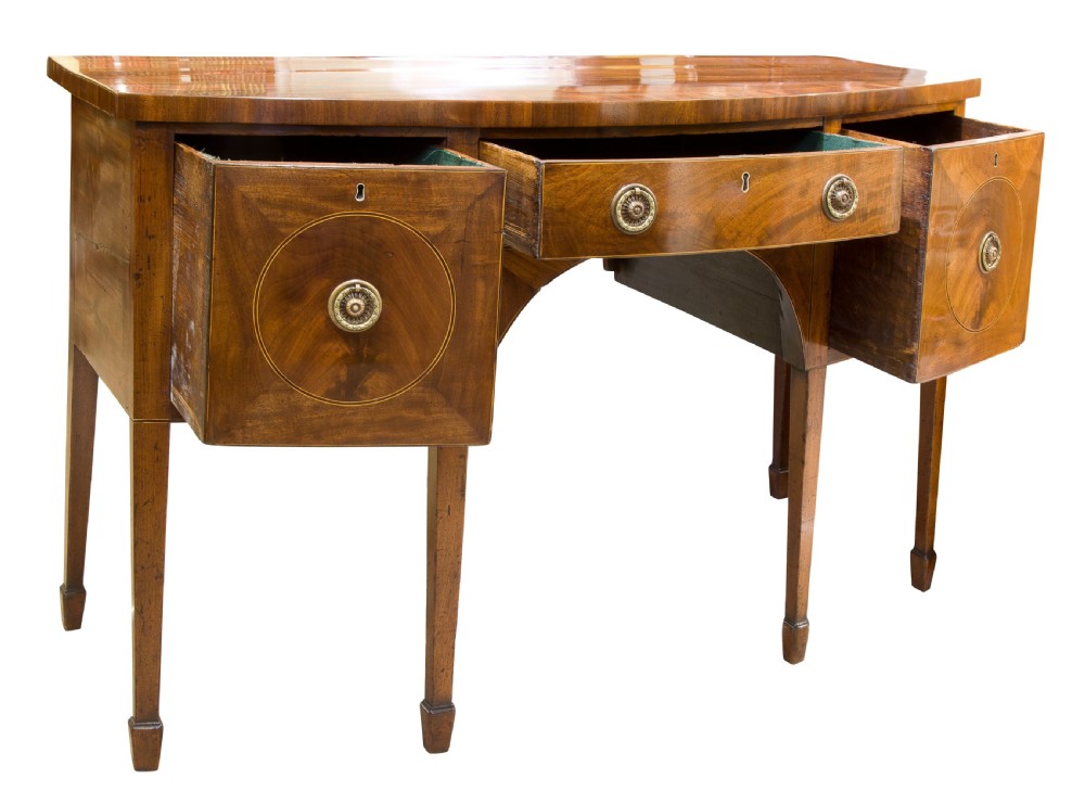 A George III mahogany bowfront sideboard featuring inlaid circular cupboard doors, a central drawer, and square tapered legs terminating in spade feet. View II
