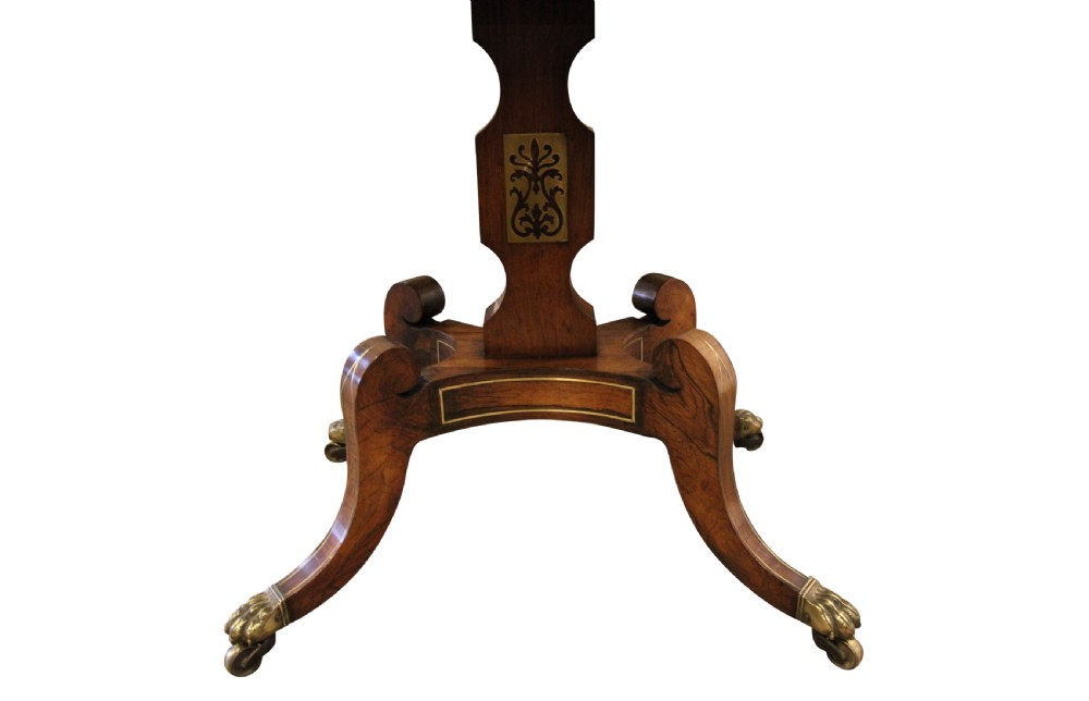 A Regency period rosewood drop-leaf work table featuring two drawers with circular brass knobs, supported by a central pedestal and four curved legs with brass lion paw castors. View IV