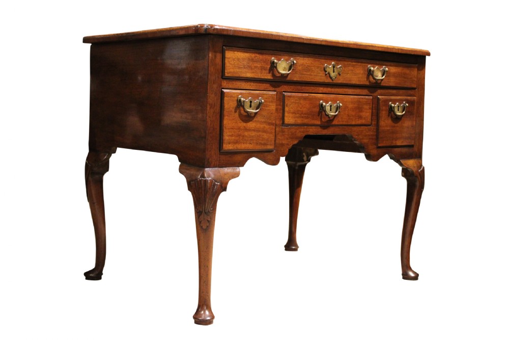 A George II mahogany lowboy table featuring carved cabriole legs, brass drop handles, and four drawers.