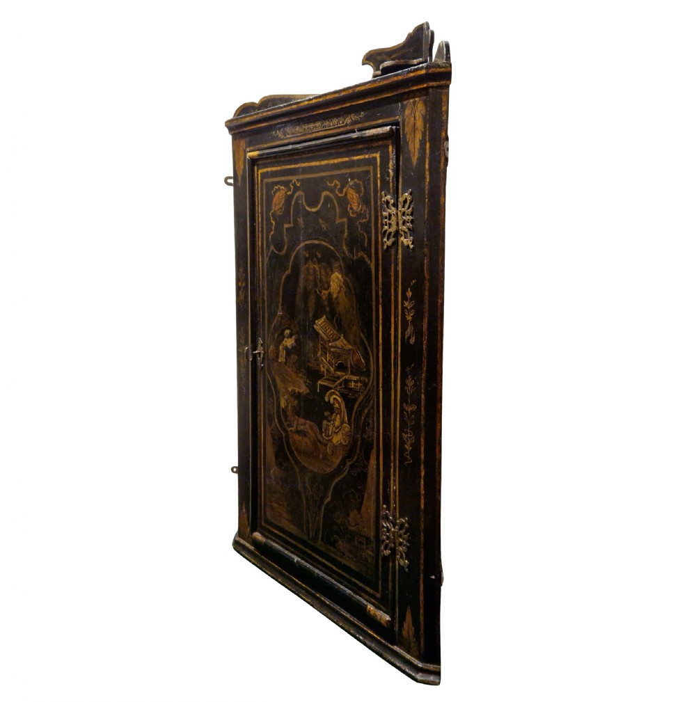An eighteenth-century black japanned corner cupboard featuring gilded Chinoiserie landscape decorations and ornate brass butterfly hinges.