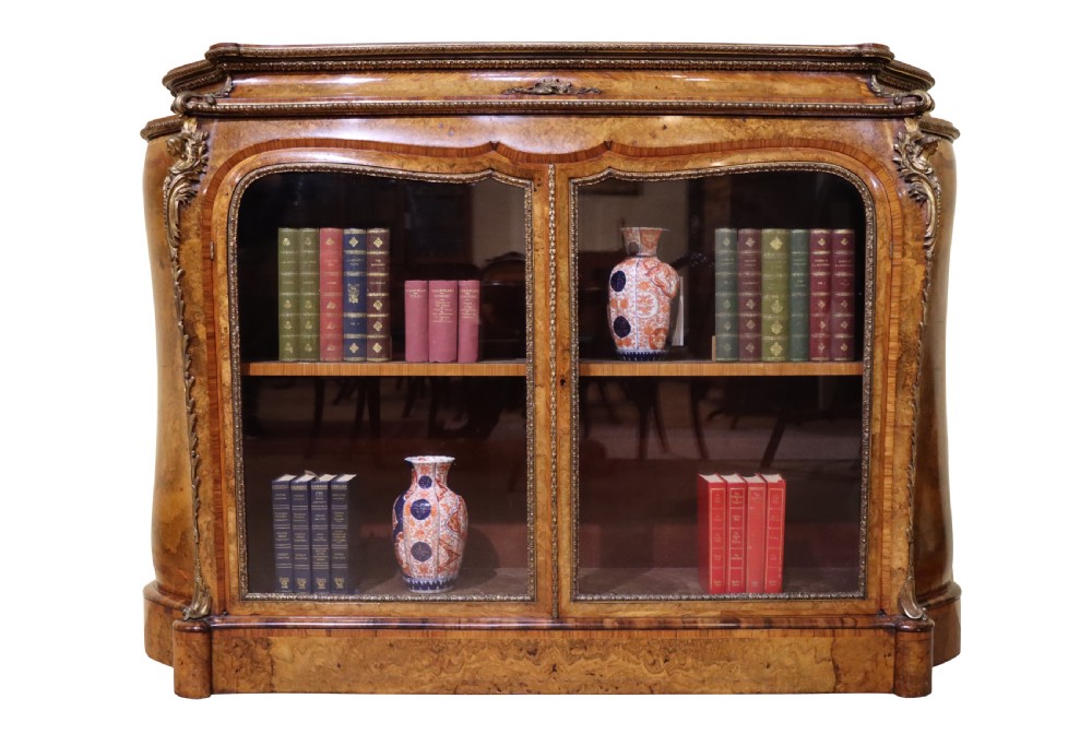 A French Revival burr walnut and kingwood side cabinet featuring two glazed doors, serpentine sides, and gilt-bronze ormolu mounts.