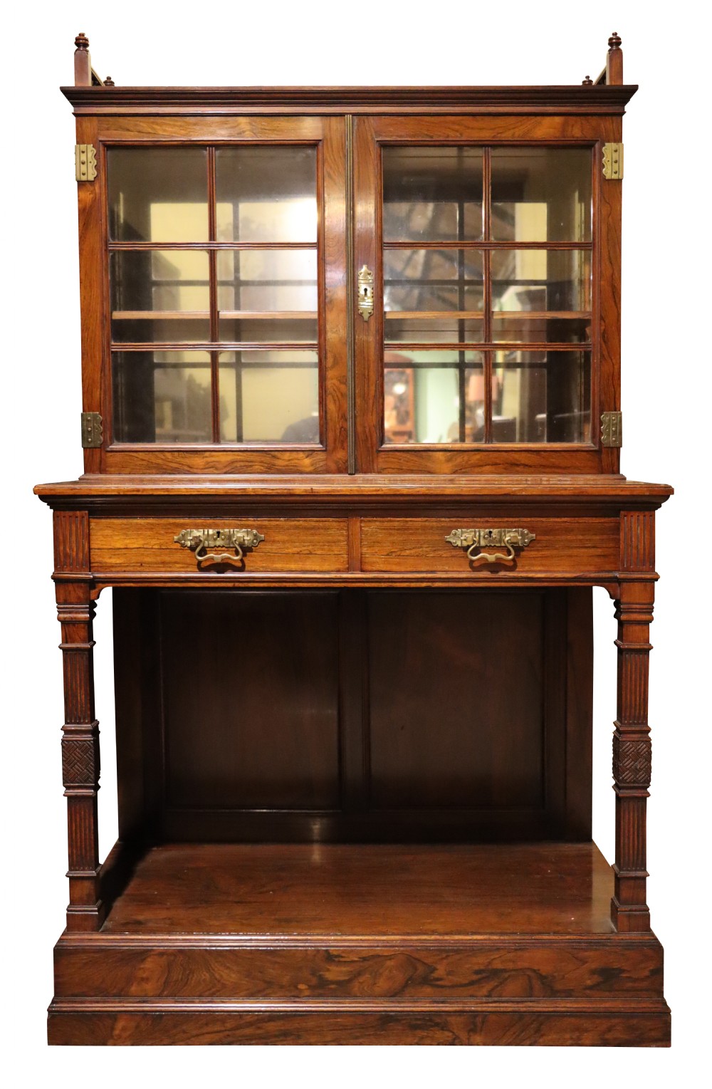An antique rosewood cabinet on stand featuring glazed double doors, brass corner mounts, two frieze drawers, and an open lower shelf.
