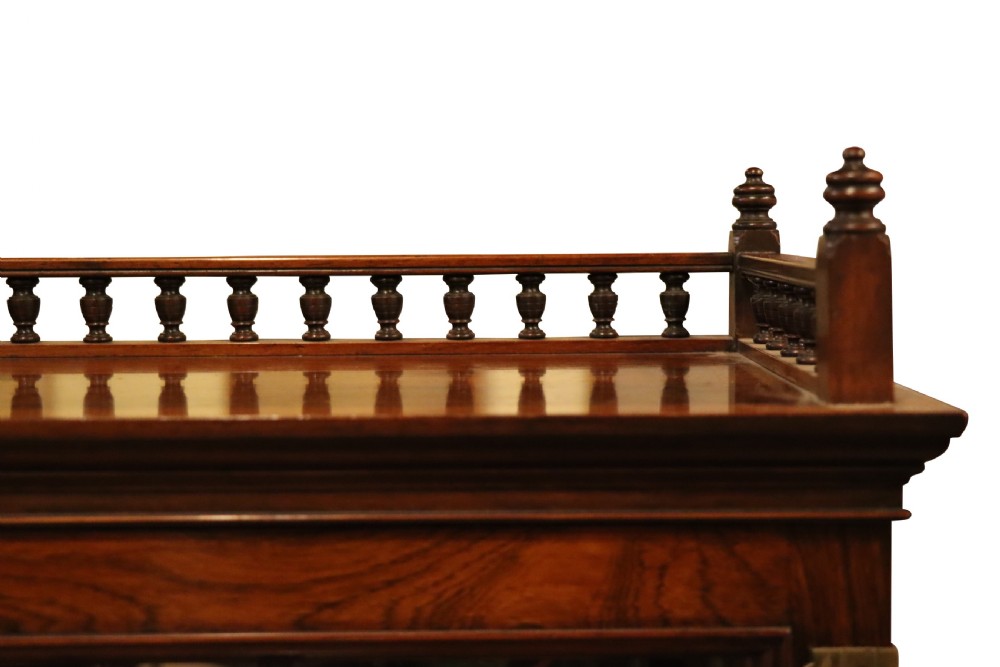 An antique rosewood cabinet on stand featuring glazed double doors, brass corner mounts, two frieze drawers, and an open lower shelf. View V