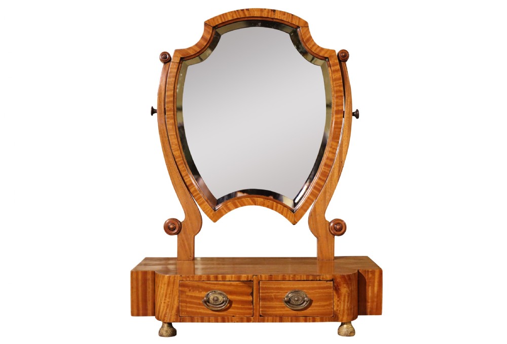 A freestanding antique satinwood dressing table mirror with a shaped bevelled glass frame set above a two-drawer base.
