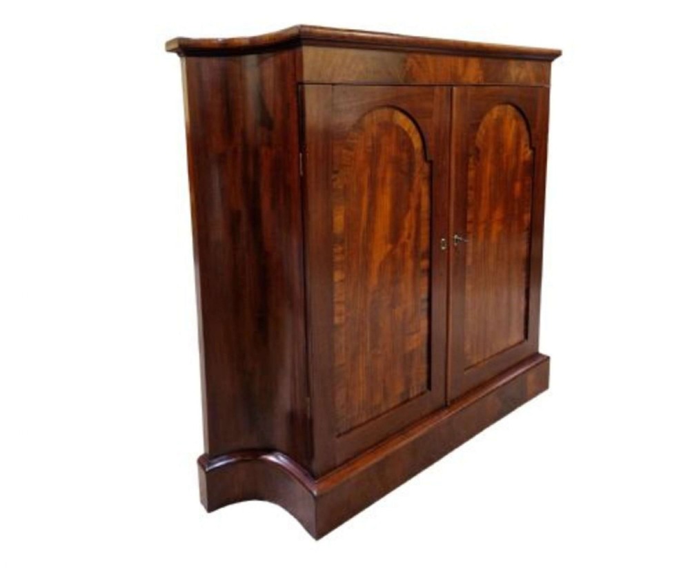 A Regency mahogany side cabinet featuring two arched panel doors, curved side panels, and a shaped plinth base.