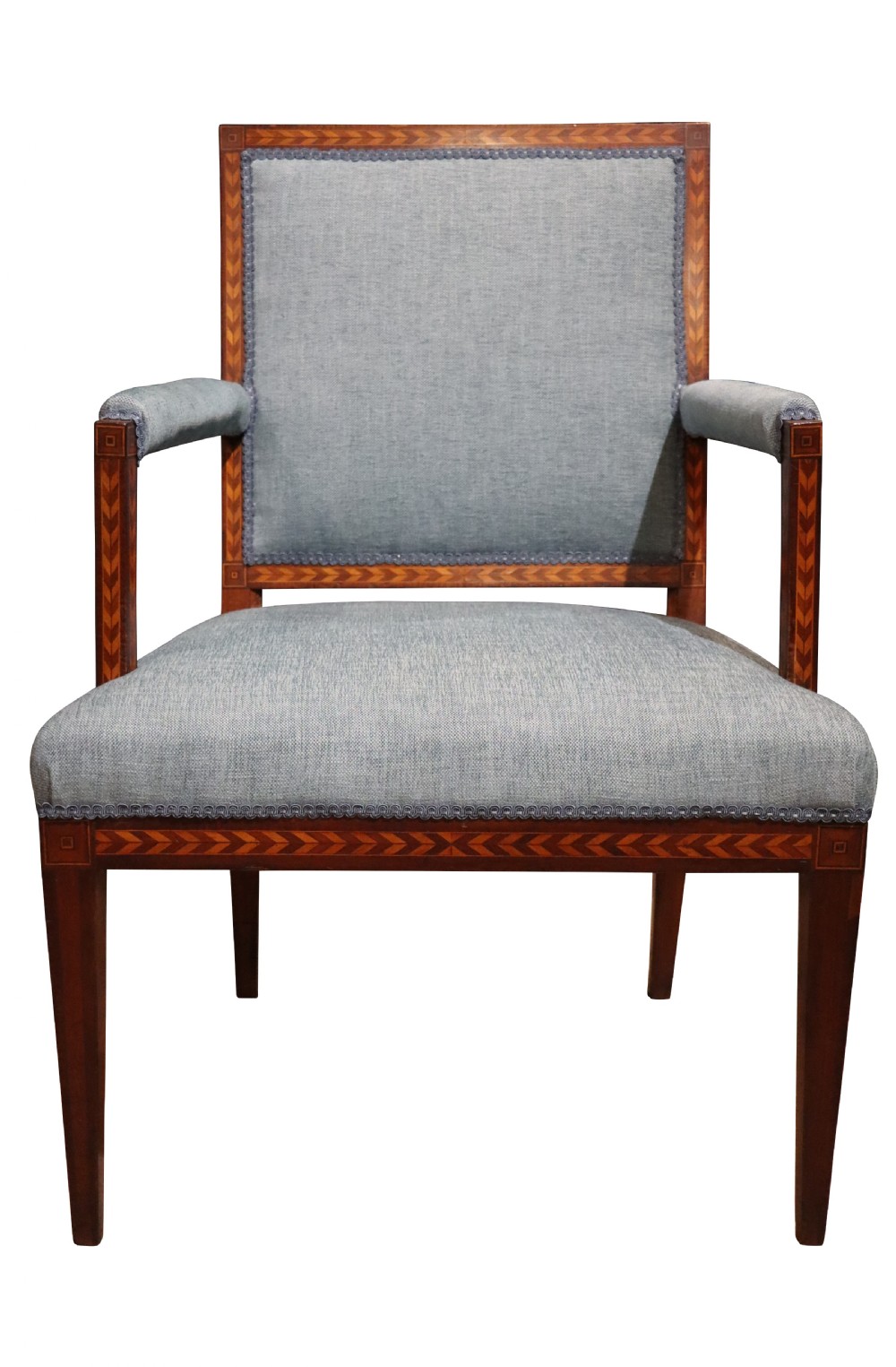A 19th-century mahogany elbow chair featuring chevron parquetry inlay, padded armrests, square tapered legs, and light blue upholstery.