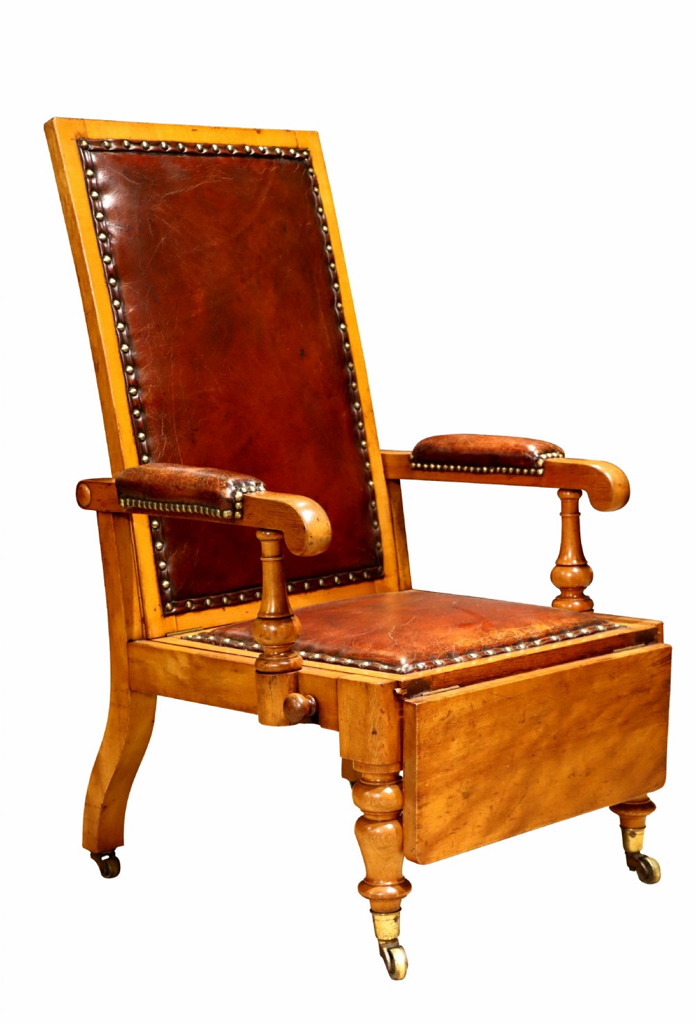 A Victorian childs reclining chair crafted from light timber with studded warm brown leather upholstery, turned arm supports, and brass castors. View II