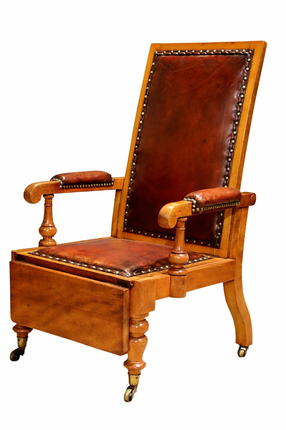 A Victorian childs reclining chair crafted from light timber with studded warm brown leather upholstery, turned arm supports, and brass castors. View IV