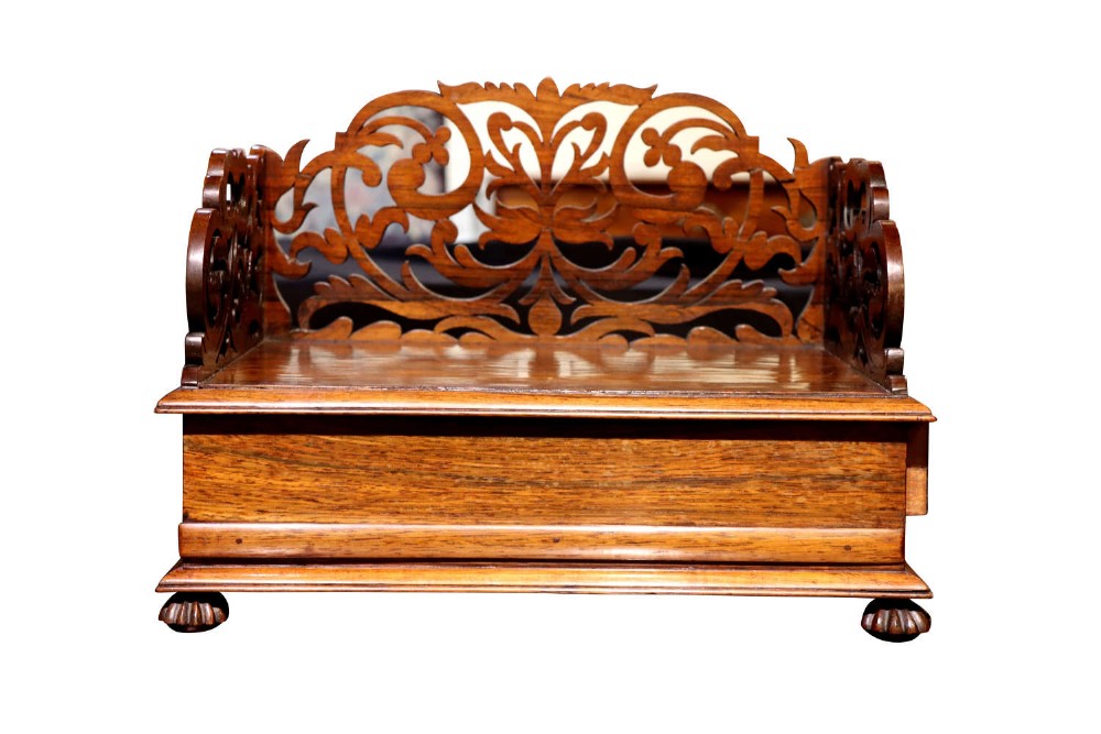 A carved rosewood desk stand featuring an ornate fretted gallery back and short claw feet.