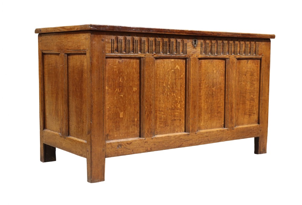 An 18th-century oak panelled coffer featuring four recessed front panels, carved frieze detailing along the top rail, and a central brass escutcheon. View II