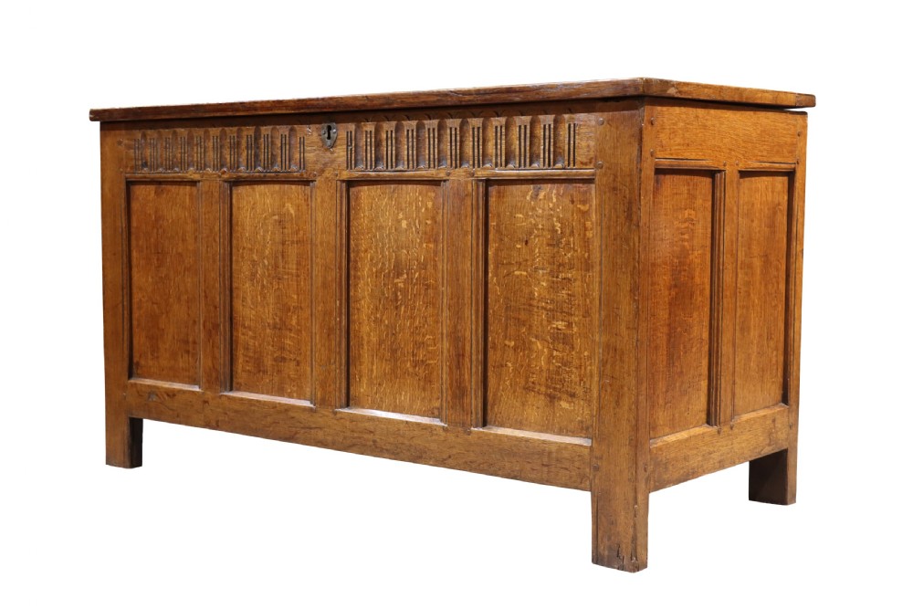 An 18th-century oak panelled coffer featuring four recessed front panels, carved frieze detailing along the top rail, and a central brass escutcheon. View IV