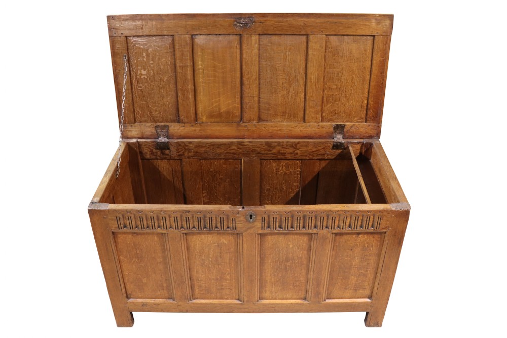 An 18th-century oak panelled coffer featuring four recessed front panels, carved frieze detailing along the top rail, and a central brass escutcheon. View V