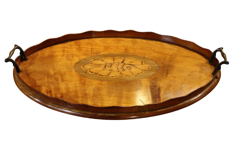 An oval Georgian mahogany serving tray featuring a scalloped gallery rim, dual brass handles, and a central marquetry shell inlay.