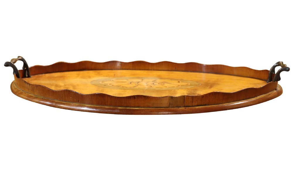 An oval Georgian mahogany serving tray featuring a scalloped gallery rim, dual brass handles, and a central marquetry shell inlay. View II
