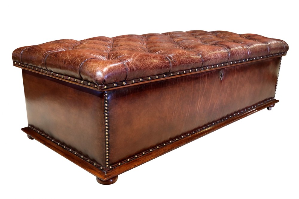 A large 19th-century rectangular leather ottoman with deep buttoned upholstery, brass stud trim, and short wooden feet on castors. View II