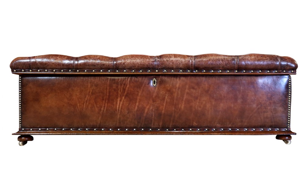 A large 19th-century rectangular leather ottoman with deep buttoned upholstery, brass stud trim, and short wooden feet on castors. View III