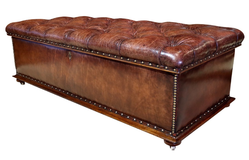 A large 19th-century rectangular leather ottoman with deep buttoned upholstery, brass stud trim, and short wooden feet on castors. View IV