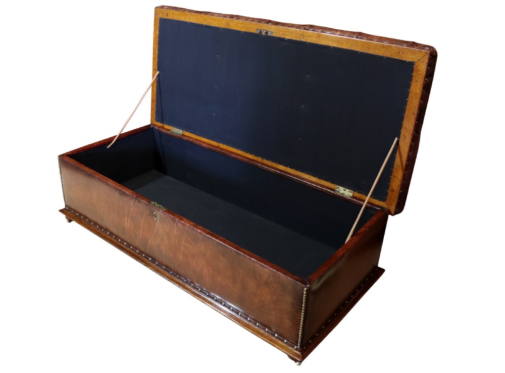 A large 19th-century rectangular leather ottoman with deep buttoned upholstery, brass stud trim, and short wooden feet on castors. View V