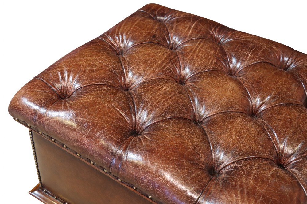 A large 19th-century rectangular leather ottoman with deep buttoned upholstery, brass stud trim, and short wooden feet on castors. View VI