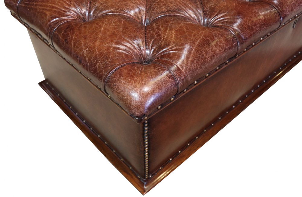 A large 19th-century rectangular leather ottoman with deep buttoned upholstery, brass stud trim, and short wooden feet on castors. View VII