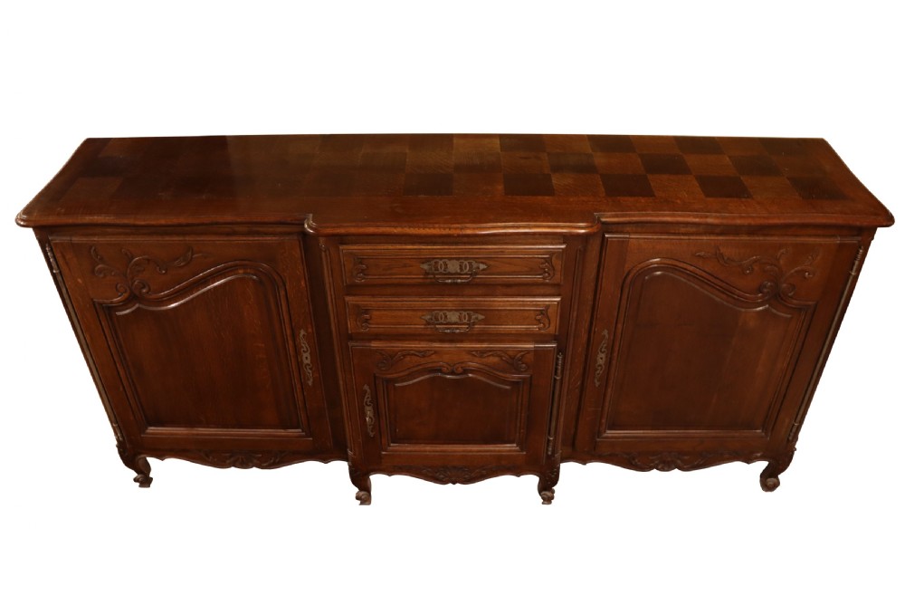 A French Louis XV style warm brown oak sideboard featuring three carved panel doors, two central drawers, brass hardware, and cabriole feet. View V