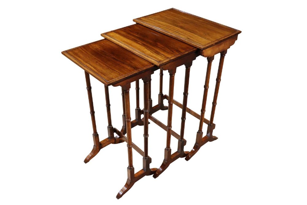 A set of three Regency rosewood nesting tables with rectangular reeded tops supported by thin turned legs and trestle bases.