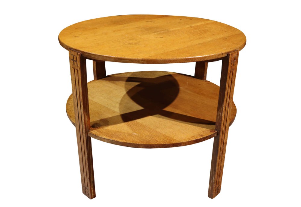 A circular two-tier light oak Art Deco coffee table featuring four straight legs with carved geometric fluting.