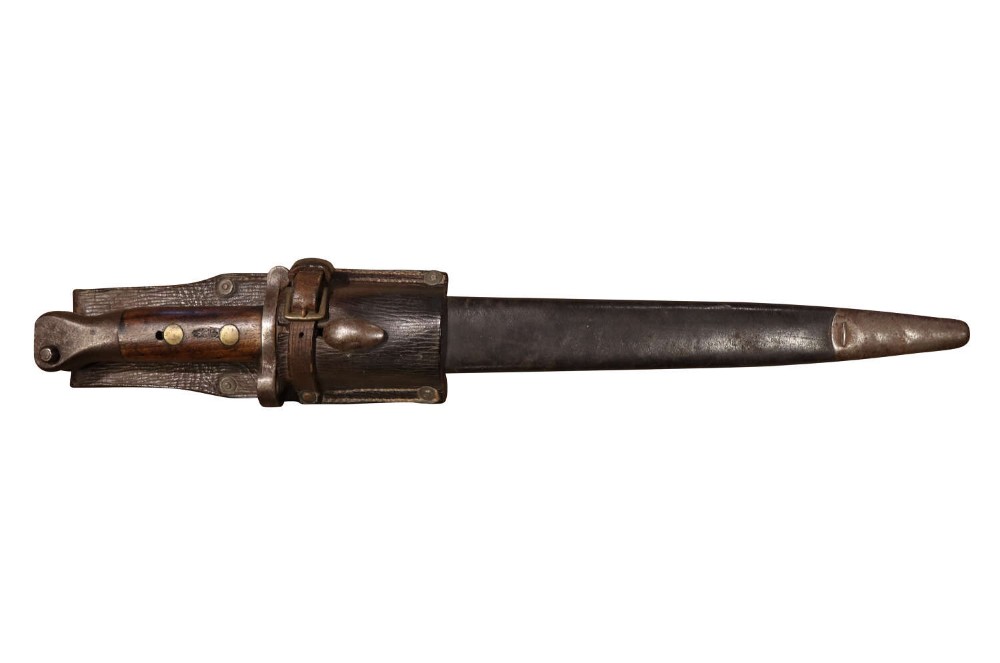 A late Victorian Lee-Metford pattern bayonet shown housed in a leather scabbard with an attached leather belt frog.