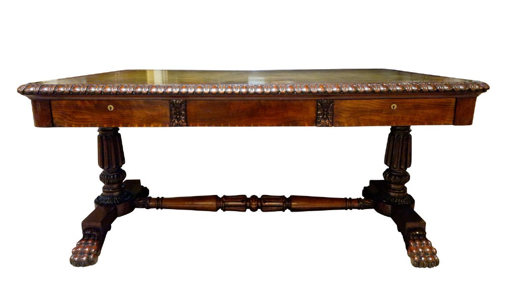 A George IV mahogany partners writing table featuring a patterned top edge, three frieze drawers, carved pedestal supports, a turned stretcher, and claw feet. View II