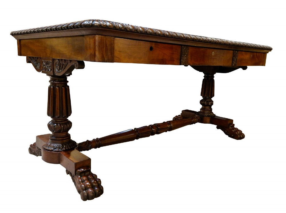 A George IV mahogany partners writing table featuring a patterned top edge, three frieze drawers, carved pedestal supports, a turned stretcher, and claw feet. View V