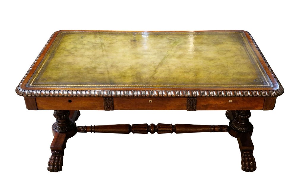 A George IV mahogany partners writing table featuring a patterned top edge, three frieze drawers, carved pedestal supports, a turned stretcher, and claw feet. View VI