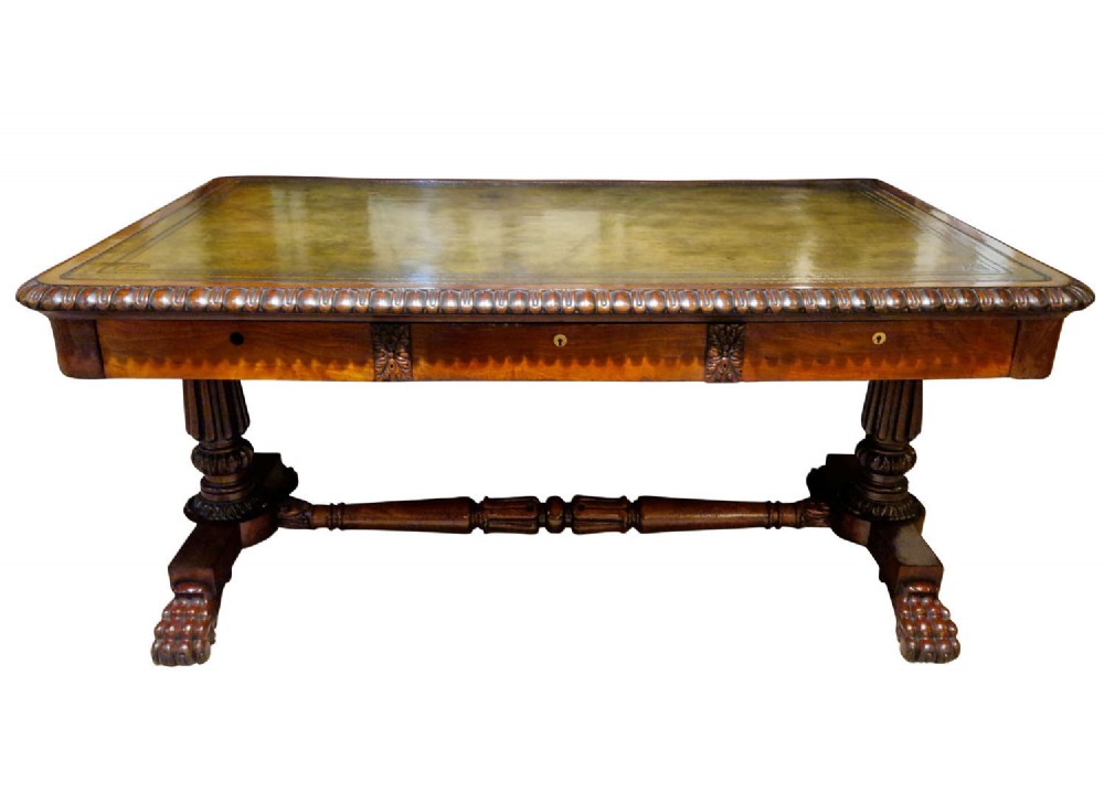 A George IV mahogany partners writing table featuring a patterned top edge, three frieze drawers, carved pedestal supports, a turned stretcher, and claw feet. View VII