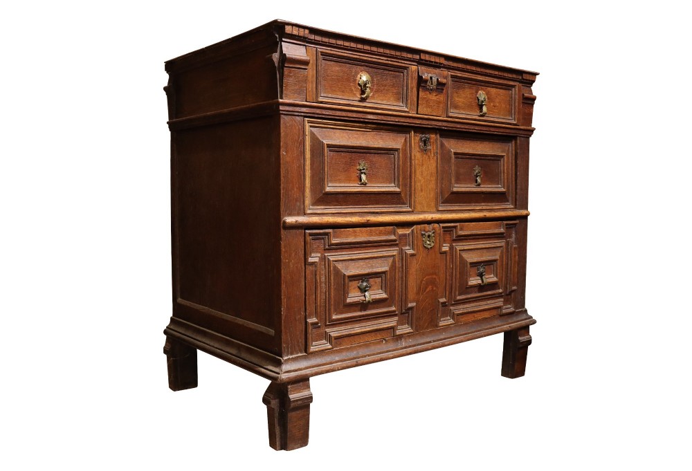 A Charles II dark oak chest of drawers featuring deep geometric mitred mouldings on the drawer fronts and brass drop handles. View II