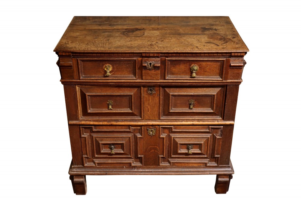 A Charles II dark oak chest of drawers featuring deep geometric mitred mouldings on the drawer fronts and brass drop handles. View III
