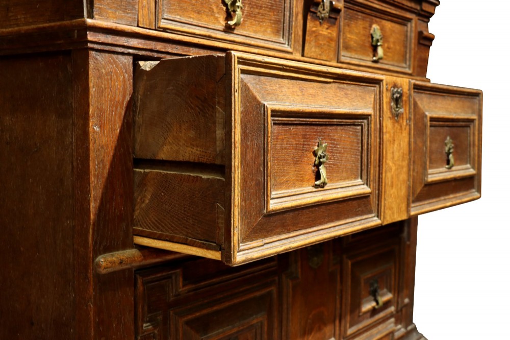 A Charles II dark oak chest of drawers featuring deep geometric mitred mouldings on the drawer fronts and brass drop handles. View V